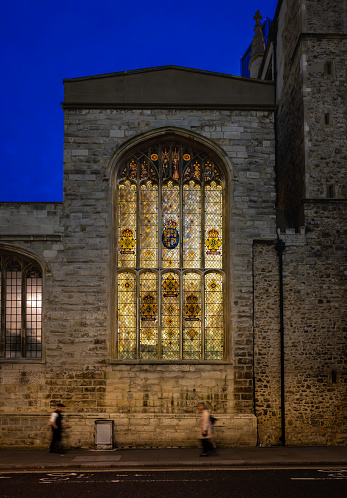 London, UK: St Andrew Undershaft Church on St Mary Axe in the City of London at night with stained glass window illuminated from behind.