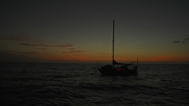 SLO MO Shot of Boat Sailing in Idyllic Ocean against Orange Sky at Dusk