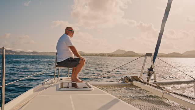 SLOW MOTION Shot of Man Sitting On Deck of Yacht Sailing in Sea On Sunny Day During Vacation
