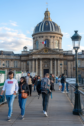 Passersby on a bridge with the French Academy building in the background on a summer day in the French capital. Paris. France. August 6, 2023.