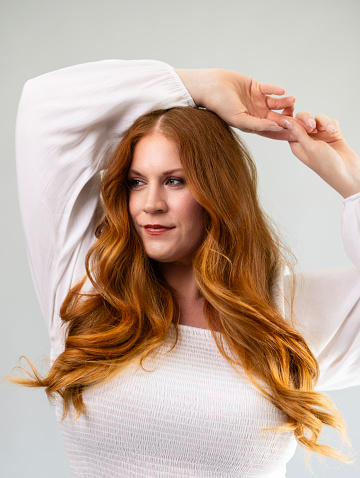 A portrait of a beautiful red haired woman on a gray background