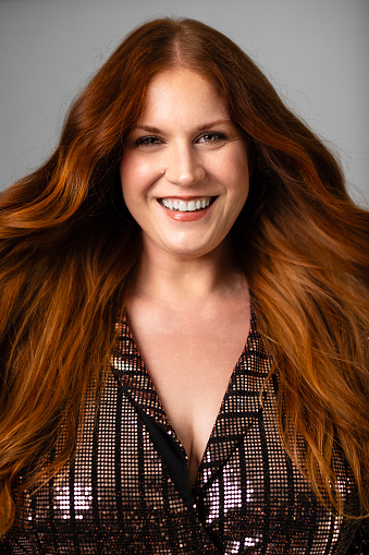 A portrait of a beautiful red haired woman on a gray background