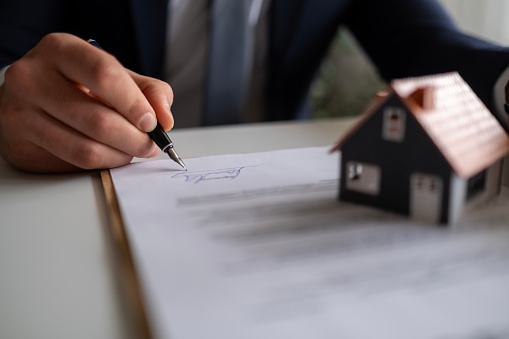 Businessman signing a legal real estate contract agreement, home Insurance.