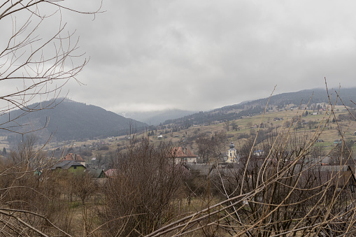 Yasinya, Ukraine. March 17, 2024, early spring, cloudy rainy sky. an incredibly beautiful view of the fog-shrouded mountains. small village houses in which people live. cozy village in the mountains