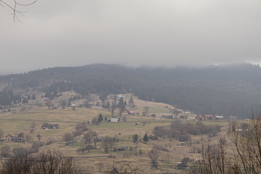 Yasinya, Ukraine. March 17, 2024, early spring, cloudy rainy sky. an incredibly beautiful view of the fog-shrouded mountains. small village houses in which people live. cozy village in the mountains