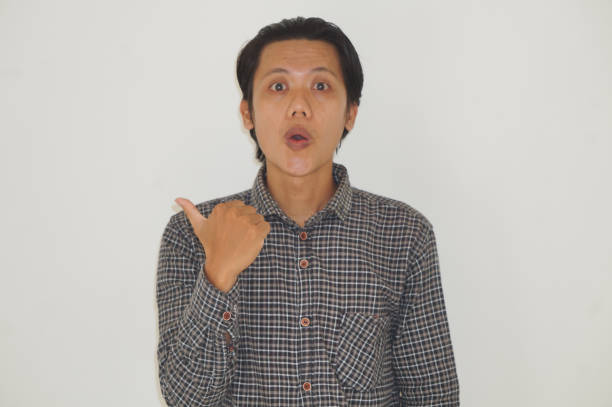 Young asian man wearing black shirt smiling pointing with hand finger to the side