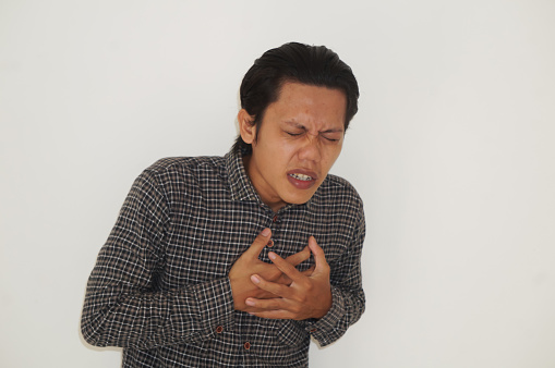 Asian young man in black shirt with chest pain expression. Isolated on white background.