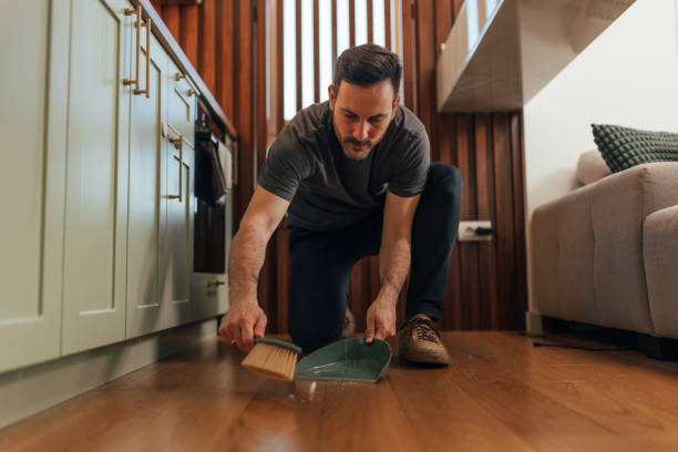 istock Man sweeping dust from floor with hand brush 2125930359