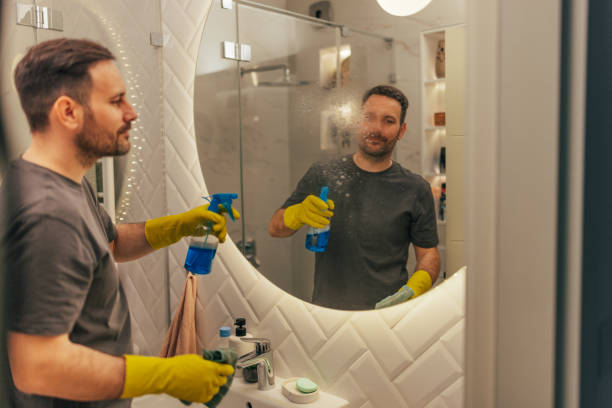 istock Man cleaning mirror with spray and cloth 2125937564