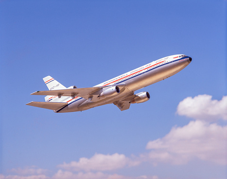 California, USA - between 1972 and 1988: Side view of DC-10-30 airplane flying in blue sky. The DC-10-30 was produced from 1972-1988. The last commercial passenger flight was in 2014. Image was made with film - airplane is a model .