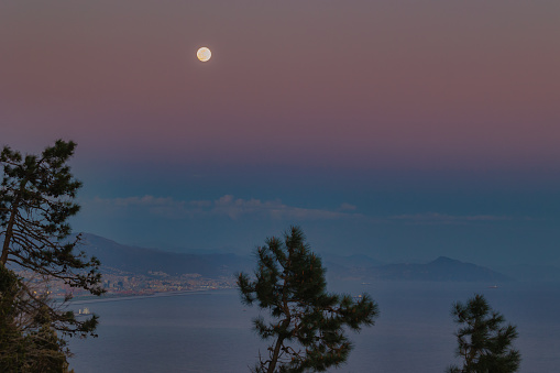 View of Genoa at sunset with a full moon.