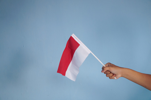 Hand holding a red and white Indonesia flag