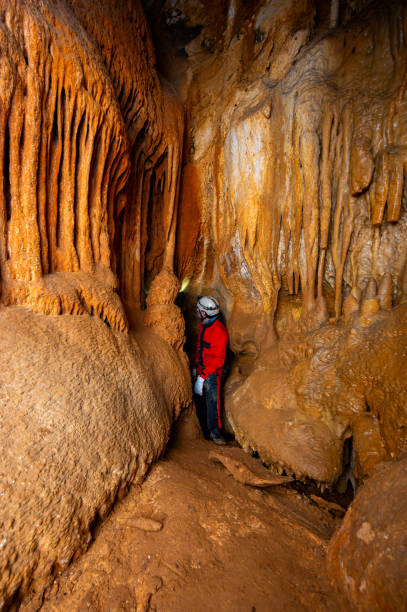 istock A speleologist with helmet and headlamp exploring a cave with rich stalactite and stalagmite formations. 2126011188