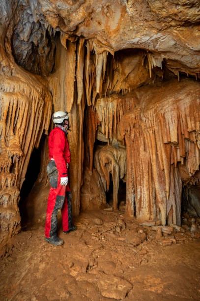 istock A speleologist with helmet and headlamp exploring a cave with rich stalactite and stalagmite formations. 2126012208