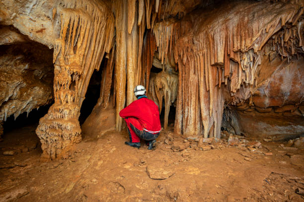 istock A speleologist with helmet and headlamp exploring a cave with rich stalactite and stalagmite formations. 2126012713