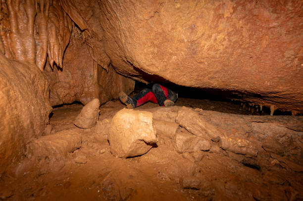 istock A speleologist with helmet and headlamp exploring a cave with rich stalactite and stalagmite formations. 2126013735