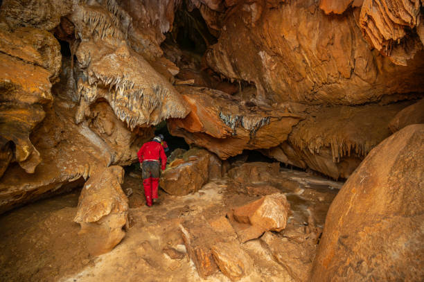istock A speleologist with helmet and headlamp exploring a cave with rich stalactite and stalagmite formations. 2126014793