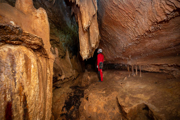 istock A speleologist with helmet and headlamp exploring a cave with rich stalactite and stalagmite formations. 2126015301