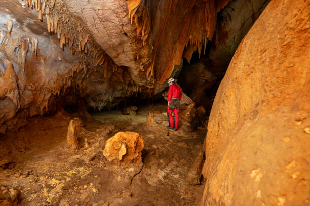 istock A speleologist with helmet and headlamp exploring a cave with rich stalactite and stalagmite formations. 2126016844