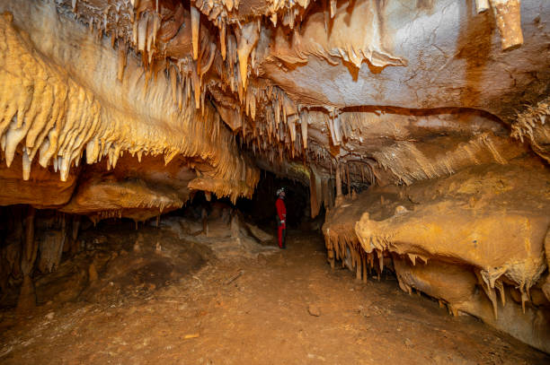 istock A speleologist with helmet and headlamp exploring a cave with rich stalactite and stalagmite formations. 2126017347