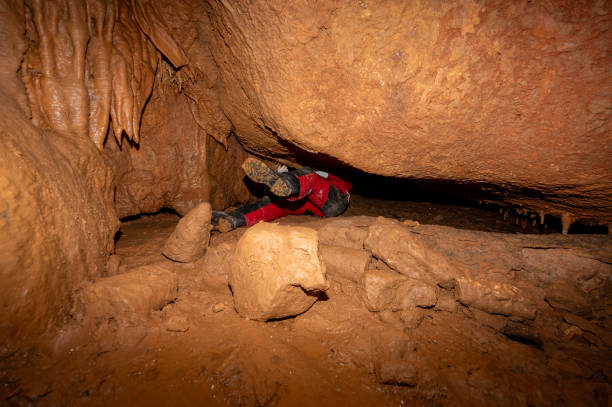 istock A speleologist with helmet and headlamp exploring a cave with rich stalactite and stalagmite formations. 2126017856
