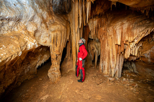 istock A speleologist with helmet and headlamp exploring a cave with rich stalactite and stalagmite formations. 2126018364