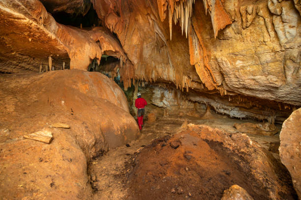 istock A speleologist with helmet and headlamp exploring a cave with rich stalactite and stalagmite formations. 2126018867