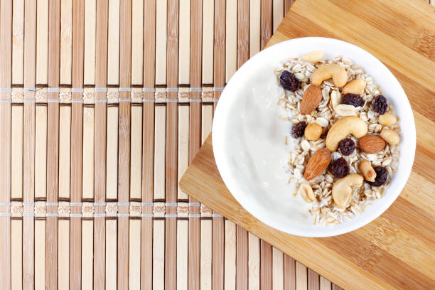 natural yogurt with homemade granola and nuts in ceramic bowl on a table top view. Healthy eating concept