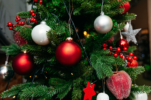 A richly adorned Christmas tree with shiny red and white baubles, berry clusters, and twinkling lights, capturing the spirit of the holiday season.