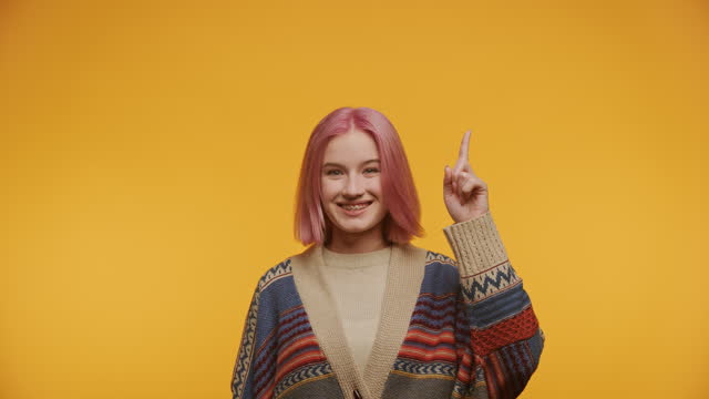 Confident Young Woman with Pink Hair Pointing Up