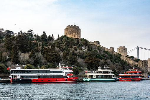 Istanbul, Turkey  March 19, 2024 Ferry boats in Bosporus docked at the foot of the Rumeli Fortress.