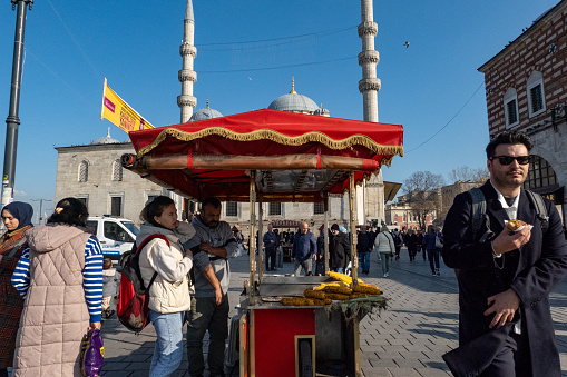 Istanbul, Turkey March 19, 2024 A snack stand and pedestrians at the landmark Yeni Cami Mosque in downtown.