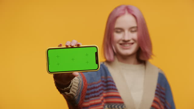 Smiling Woman Showing Smartphone with Green Screen
