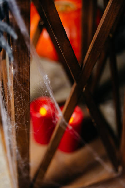 A moody Halloween scene with red candles behind cobwebs, creating a mysterious and spooky atmosphere in a dim setting.