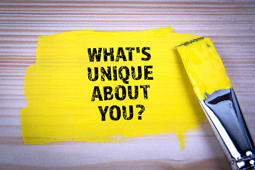 What's Unique About You. Yellow paint and paint brush on wooden texture background.