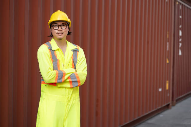 Confident cross arm Asia logistic engineer man worker or foreman working at container site