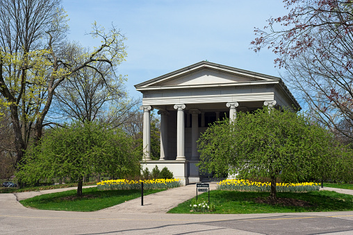 Cleveland, OH, USA - April 14, 2023: Wade Chapel, a neoclassical structure, is a frequently visited site in Cleveland's Lake View Cemetery; seen here in spring with daffodils blooming in front.