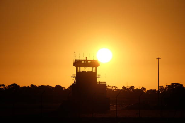 Captured during sunset time, the Parafield Airport Air Traffic Control Tower appears in silhouette with the sun in the background. This airport, ICAO YPPF,  is located in Parafield, South Australia and is listed in the Australian Commonwealth Heritage List. This is the original image without any cropping and altering processing.