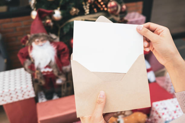 istock Woman's hand holding empty greeting card on background of christmas tree, gift box and ornaments. Merry christmas and happy new year concept 2126545371