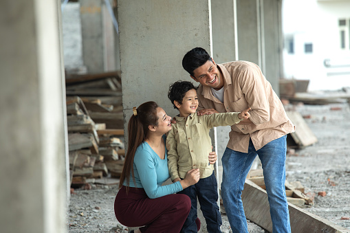 Excited young father gesturing while discussing new house plans with family at construction site