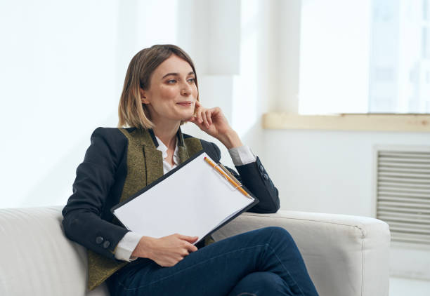 istock Business woman in suit with documents sitting on sofa 2126712187