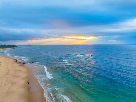 Sunrise at the seaside with cloud filled sky at Caves Beach on the Swansea peninsula in Greater Newcastle. Caves Beach is located in the Hunter-Central Coast Region of NSW, Australia.