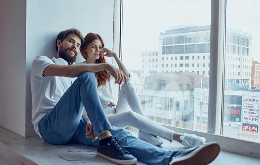 young couple sitting on the windowsill near the window rest fun lifestyle. High quality photo
