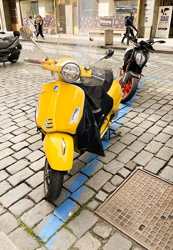 Prague, Czech Republic - March 27, 2024: Yellow italian classic scooter Vespa on a street.