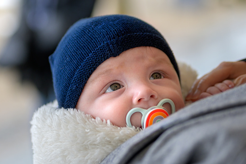 Cute little baby with pacifier on bed indoors