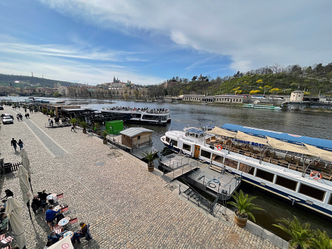 Prague, Czech Republic - March 27, 2024: Vltava river and Prague old town. People relaxing on the riverfront.