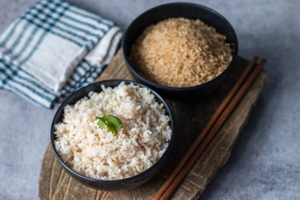 istock raw and cooked brown rice with a rock block background. 2126821330