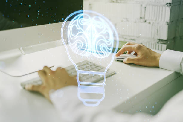 istock Creative light bulb with human brain hologram and with hands typing on computer keyboard on background, artificial Intelligence and neural networks concept. Multiexposure 2126841597