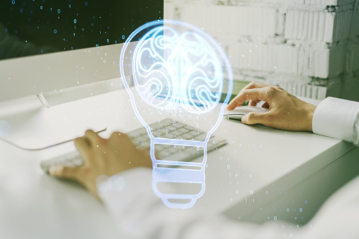 Creative light bulb with human brain hologram and with hands typing on computer keyboard on background, artificial Intelligence and neural networks concept. Multiexposure