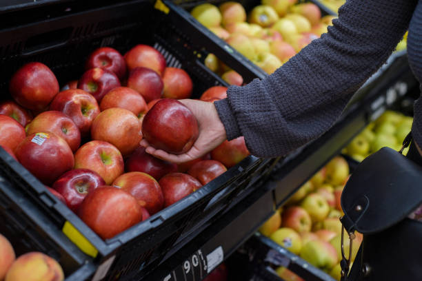 istock Hand holding an apple at a supermarket. 2126857530
